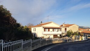 A residential area with two-story houses, a curved road, and a white metal fence.