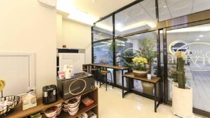 Un interior modern amb zona de seients, una màquina de cafè i una planta en test.