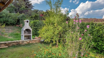 Un forno in pietra, vegetazione rigogliosa e un muro in pietra.
