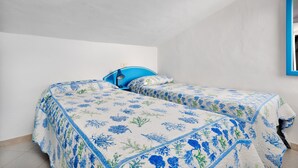 Ein Schlafzimmer mit zwei Betten, einem blauen Kopfteil und einem Spiegel an der Wand.