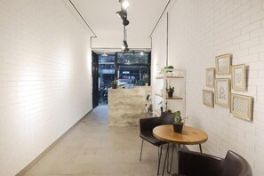 A narrow hallway with white brick walls, a round wooden table with two chairs, and a ceiling light fixture. - URVANA Hotel By Majestra Hospitality (Bogor)