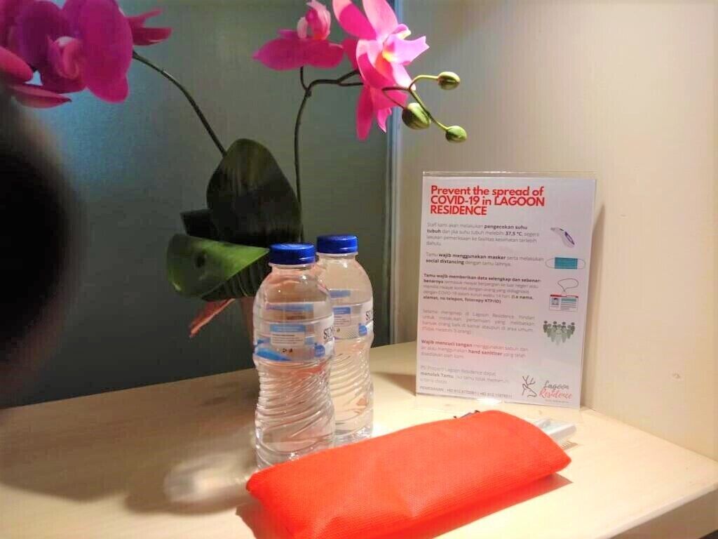 A table with two water bottles, a red cloth, and a sign about preventing COVID-19 spread in a residence.