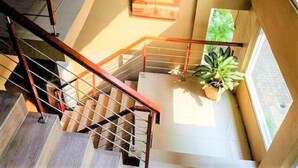 A staircase with wooden railings and a potted plant on the landing. - URVANA Hotel By Majestra Hospitality (Bogor)