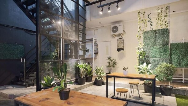 An indoor space with a staircase, potted plants, and a wall-mounted green wall. - URVANA Hotel By Majestra Hospitality (Bogor)