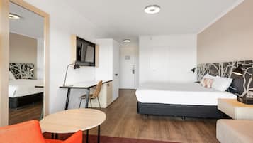 A hotel room with a bed, a desk, a chair, and a TV.
