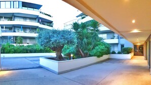 Ein moderner Hotelinnenhof mit einem zentralen Pflanzgefäß, einer Palme und einem Gebäude mit Balkonen.