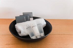 A black bowl containing a white towel and three tubes of 'pure pure vitality' shampoo and conditioner. - Bright Colonial Motel (Bright)