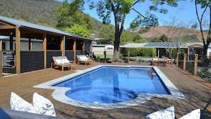 Zona de piscina con sillones de descanso y una terraza de madera.