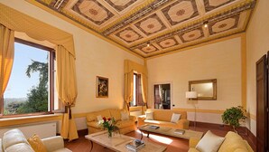 Amplia sala de estar con un sofá color beige, una mesita de centro y un ventanal con cortinas.