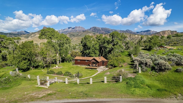 A rustic cabin with a wooden exterior, surrounded by lush greenery and mountains in the background. - Private Cottage away from Crowds (Cody)