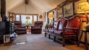 A cozy living room with leather sofas, a fireplace, and framed artwork on the walls. - Private Cottage away from Crowds (Cody)