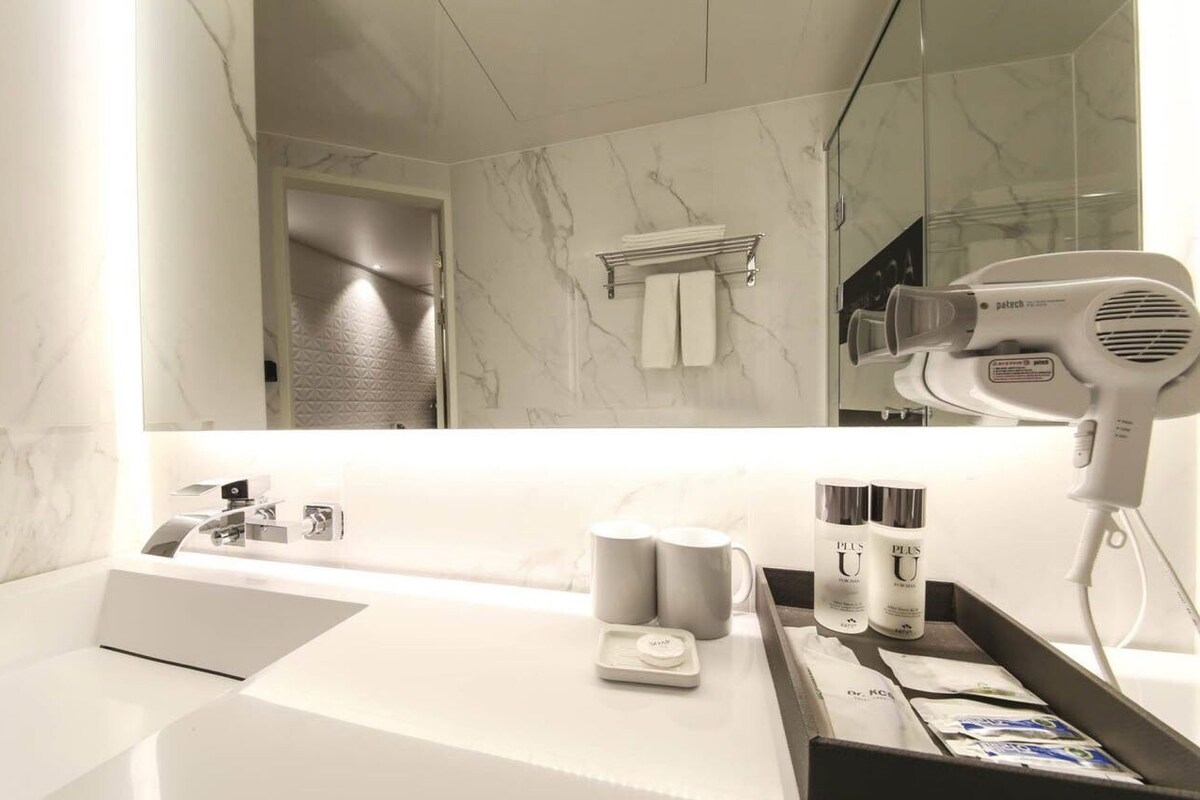 Ein modernes Badezimmer mit Waschbecken aus Marmor, Fön und Pflegeprodukten.