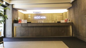 A reception desk with a sign reading "A.C.C Hotel Business Hotel" and a plant to the left. - Sinan E.KKLIM Hotel (Gwangju)