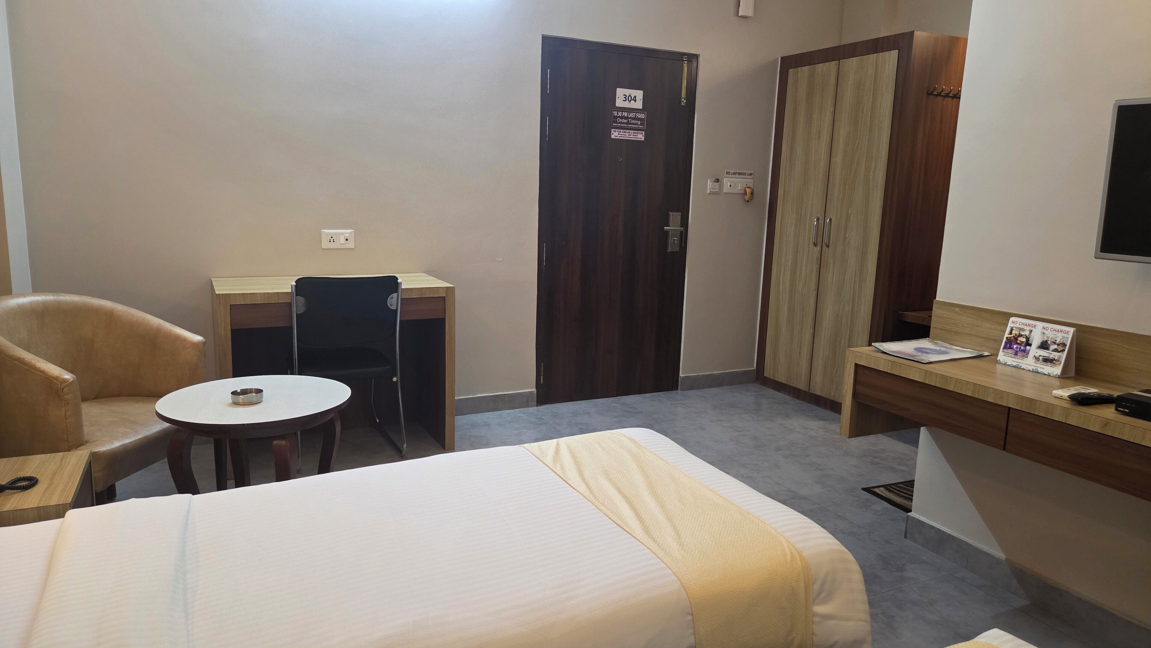 Una habitación de hotel con cama, escritorio, silla, mesita y armario.