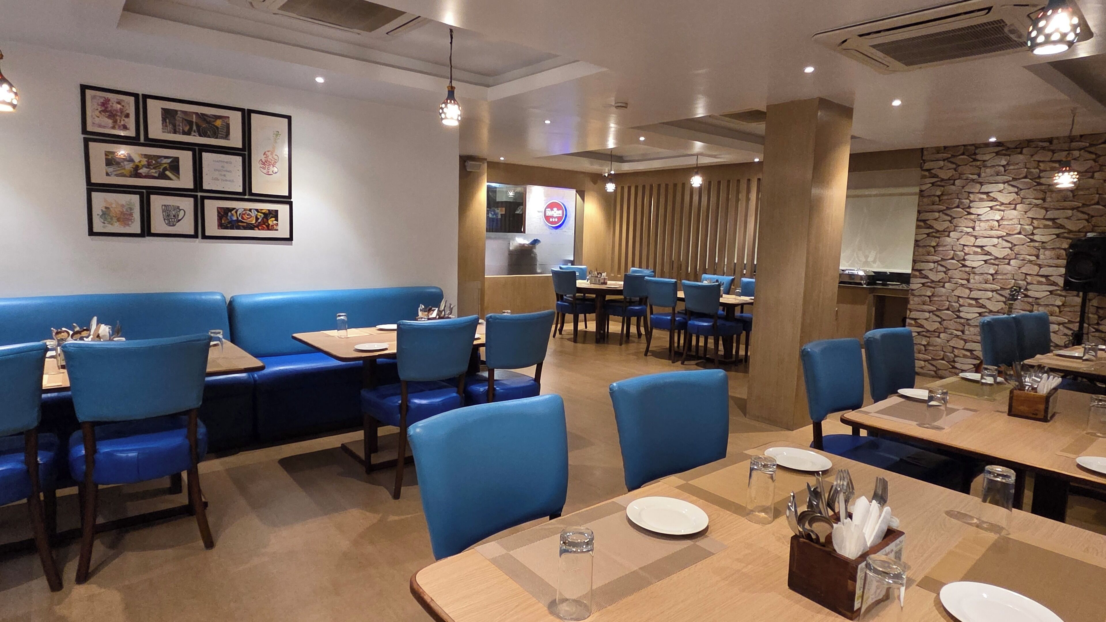 A restaurant interior with blue booths, wooden tables, and a stone accent wall.