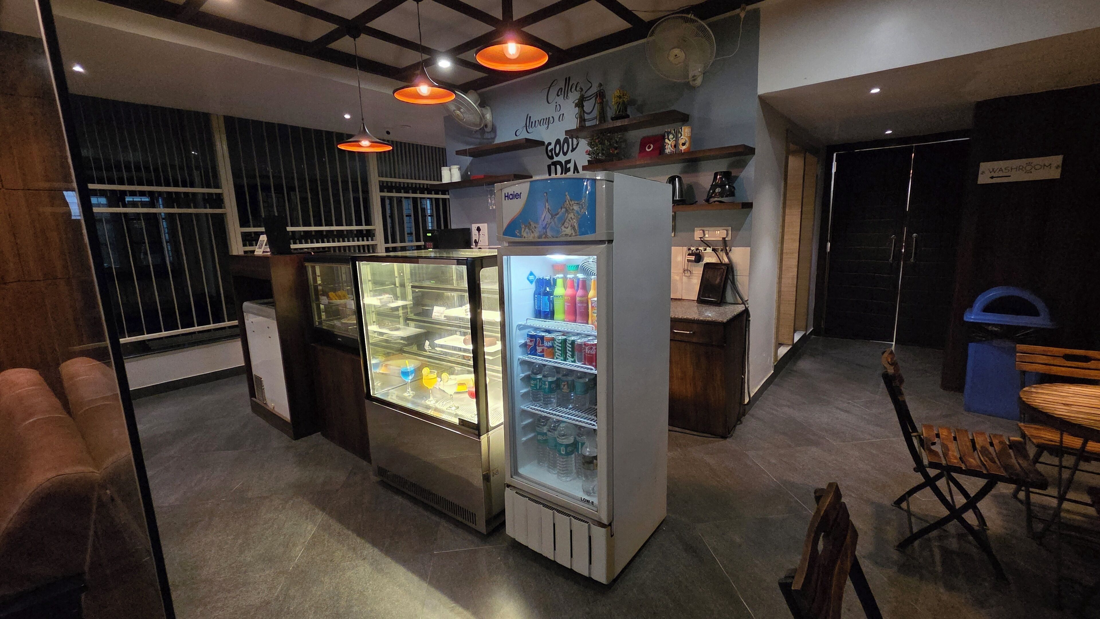 A café with a refrigerator stocked with beverages, a coffee machine, and a sign that reads "Coffee is always a good idea."