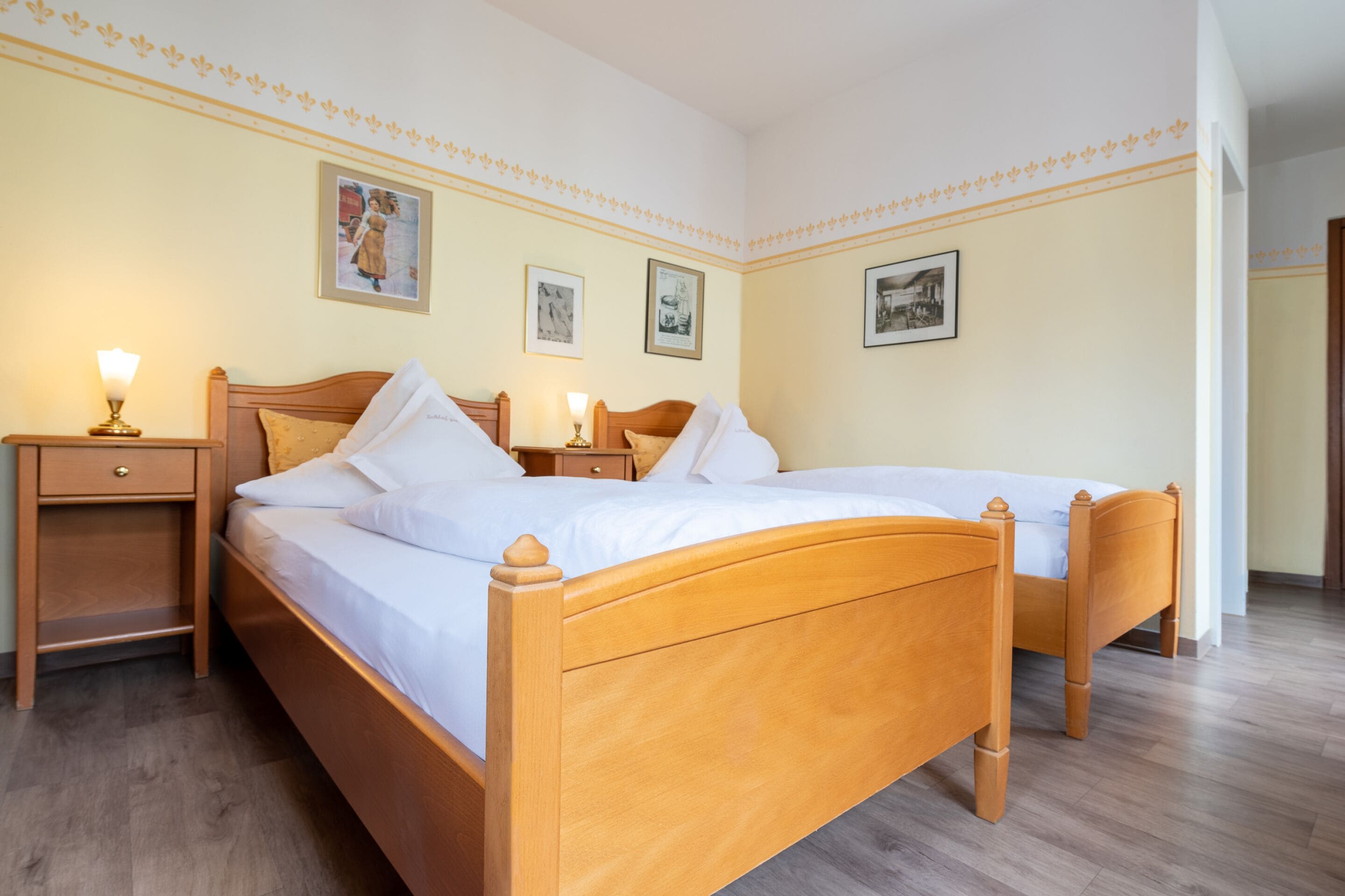 A double bed with wooden headboard, two bedside tables with lamps, and framed pictures on the wall.