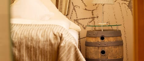 A bed with a pillow labeled "Schlaf gut," a striped blanket, and a wooden barrel with a lamp on top.