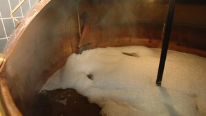 A large copper boiler filled with water and foam, with a metal handle and a light fixture above. - Brauereigasthof Flair-Hotel Sperber-Bräu (Sulzbach-Rosenberg)