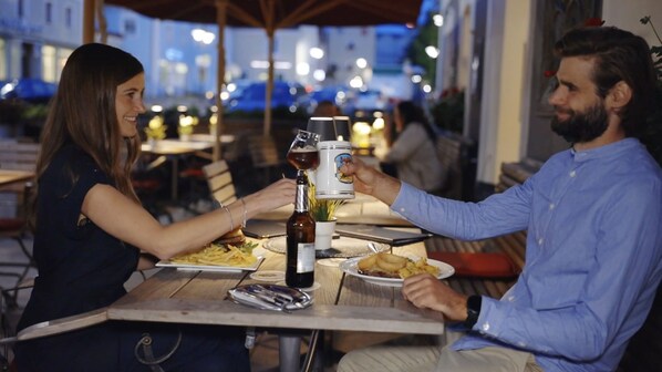 Una pareja cenando en un restaurante al aire libre con vista a la ciudad de noche.