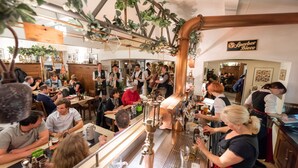 A busy bar area with copper pipes, a beer tap, and patrons seated at tables. - Brauereigasthof Flair-Hotel Sperber-Bräu (Sulzbach-Rosenberg)