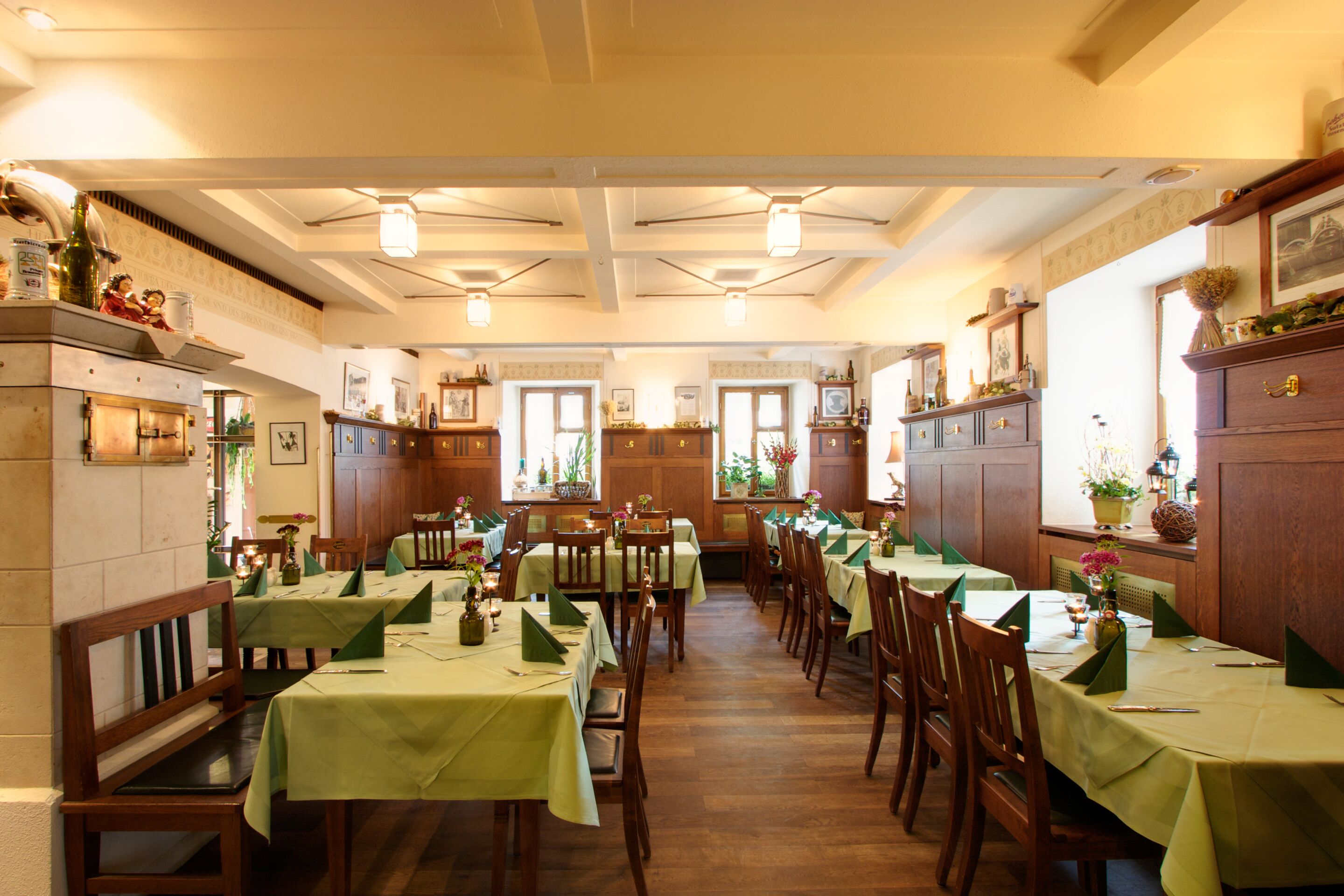 A restaurant with multiple tables and chairs, wooden paneling, and framed pictures on the walls.