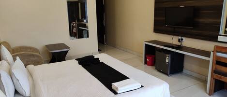 Una habitación de hotel con cama, escritorio, televisión y espejo.