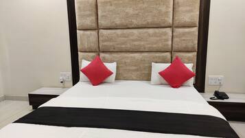 Una habitación de hotel con una cama grande, un cabecero, dos mesitas de noche y un teléfono sobre una de ellas.