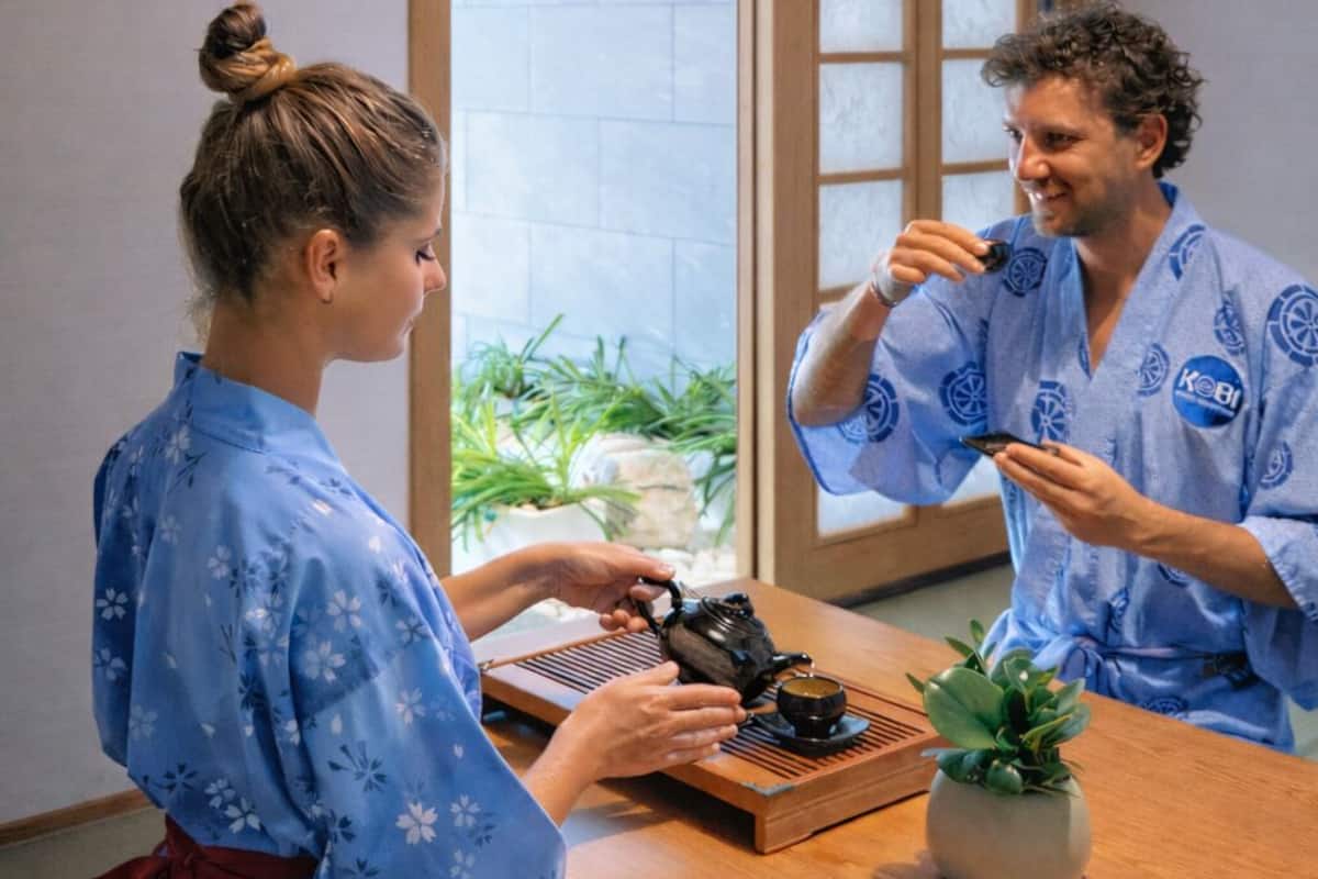Ein traditioneller japanischer Raum mit Tatami-Böden, einer Schiebetür und einem kleinen Tisch mit Teeservice.