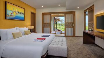 A hotel room with a large bed, a bench, a TV, and a painting on the wall.