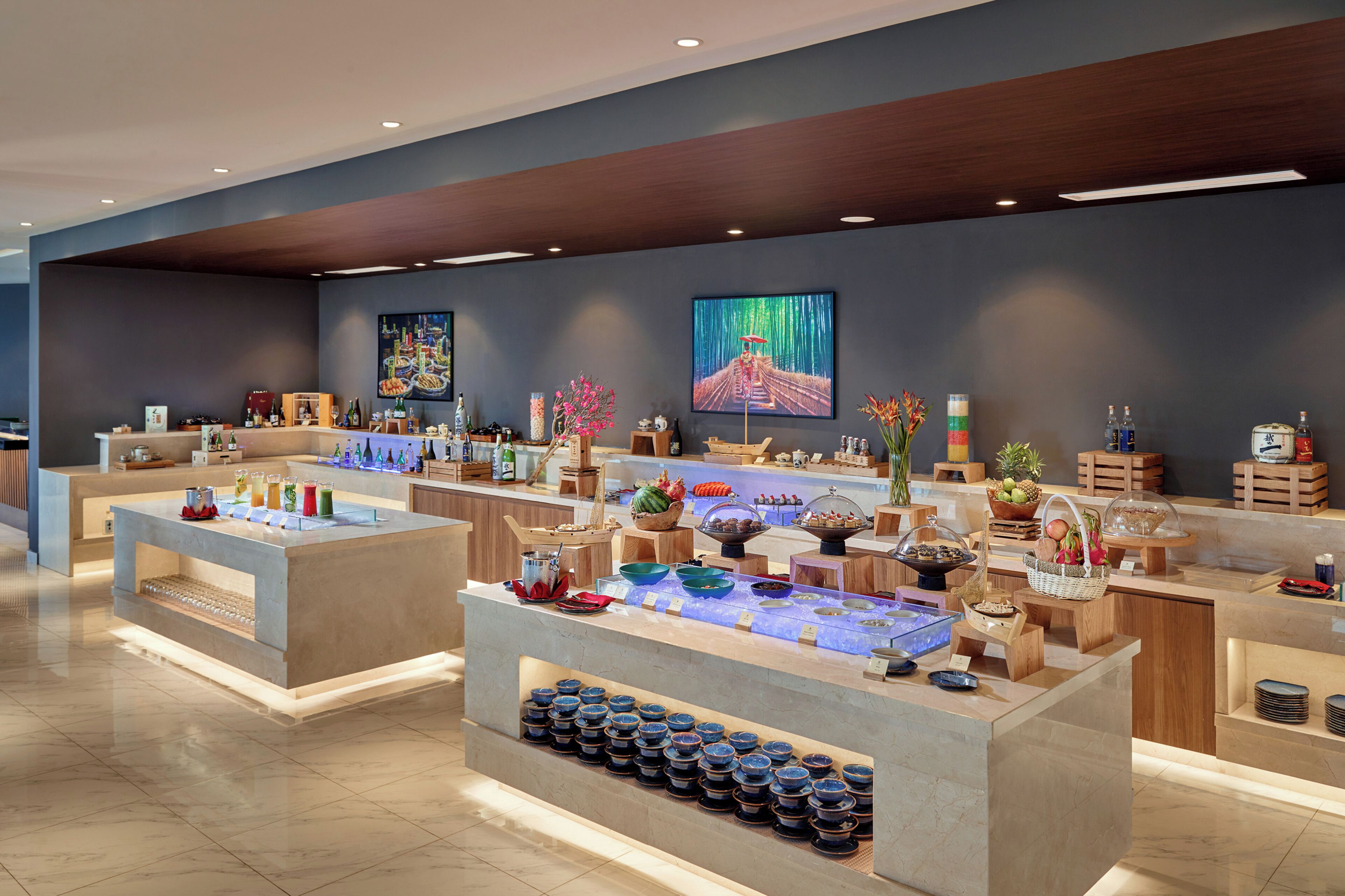 Ein modernes Buffet mit verschiedenen Speise- und Getränkestationen, darunter eine Obstauslage und eine Bar.