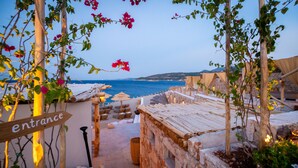 A stone pathway leading to a beachside area with a wooden entrance sign. - Aliv Stone Suites & Spa (Zakynthos)