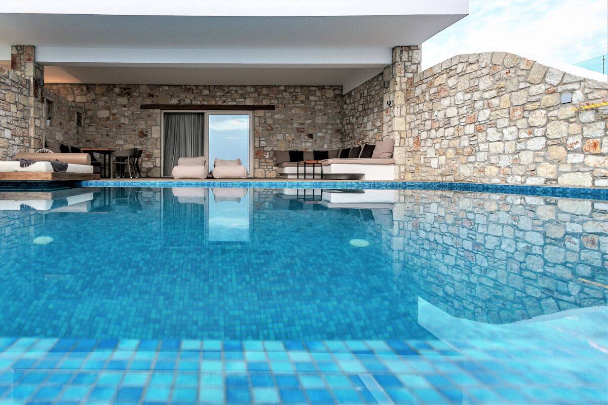A modern indoor pool with stone walls and a clear blue pool.