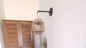 A room with a wooden wardrobe, a black tray table with a tea set, a vase with dried flowers, and a wall-mounted light fixture. - Stalis Drops (Hersonissos)
