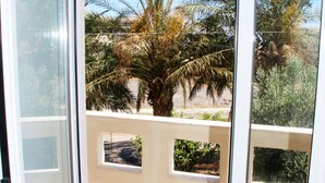A sliding glass door leading to a balcony with a view of palm trees and a tiled floor. - Stalis Drops (Hersonissos)