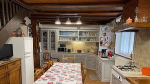 A compact kitchen with a dining table, chairs, a refrigerator, a microwave, and a gas stove. - Individual countryside house in a small village (Cercles)