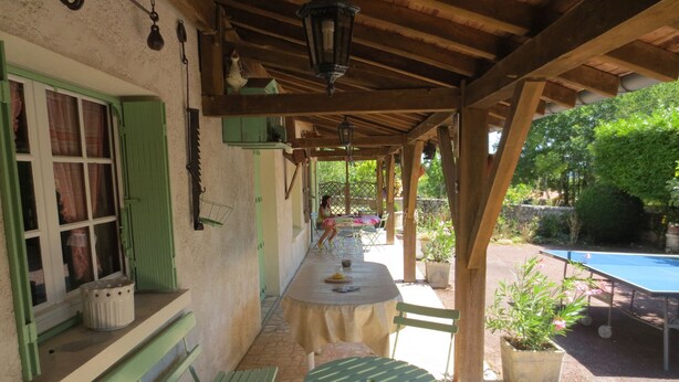 An outdoor patio with a table and chairs, a pool, and potted plants. - Individual countryside house in a small village (Cercles)