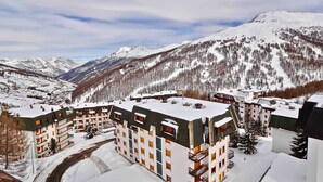 A snow-covered mountain resort with multi-story buildings, ski slopes, and a clear sky. - Two-room apartment with panoramic views in Sestriere (Sestriere)