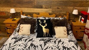A bed with a patterned bedspread, two pillows with deer designs, and a wooden headboard. - Two-room apartment with panoramic views in Sestriere (Sestriere)