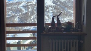 A room with a large window overlooking a snow-covered mountain. - Two-room apartment with panoramic views in Sestriere (Sestriere)