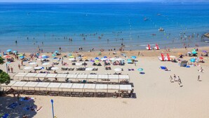Una playa con tumbonas, sombrillas y una cabaña.