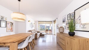 Una cocina moderna con una mesa de comedor de madera, sillas blancas y un ventanal grande.
