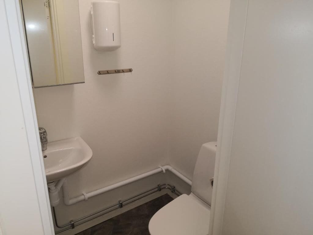 Un baño pequeño y limpio con inodoro, lavamanos y espejo.