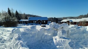 Un paisaje nevado con una casa y un muñeco de nieve.