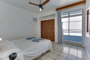 A hotel room with a bed, ceiling fan, and a view of the sea through a sliding glass door. - Marazul Apart Hotel II (Florianopolis)