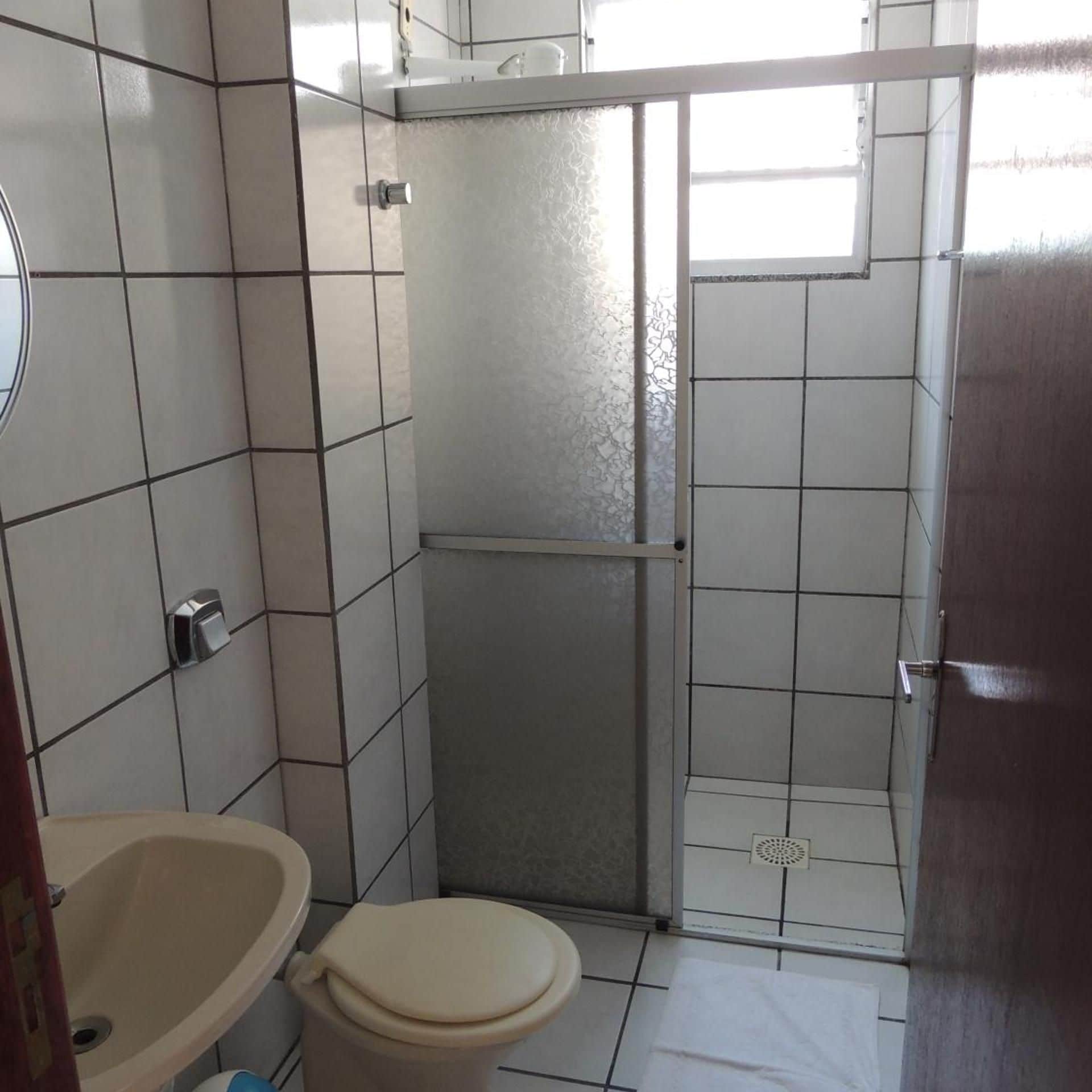 A bathroom with a toilet, sink, and shower area.
