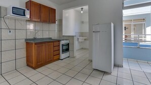 A kitchen with wooden cabinets, a microwave, an oven, and a refrigerator. - Marazul Apart Hotel II (Florianopolis)