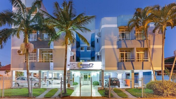 A modern hotel with a central entrance, multiple floors, and a parking area. - Marazul Apart Hotel II (Florianopolis)