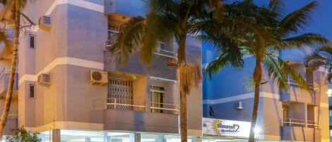 A multi-story hotel with a modern design, featuring balconies and a well-lit entrance.