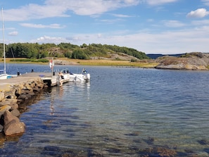 A dock with a boat, clear water, and a hilly landscape in the background.